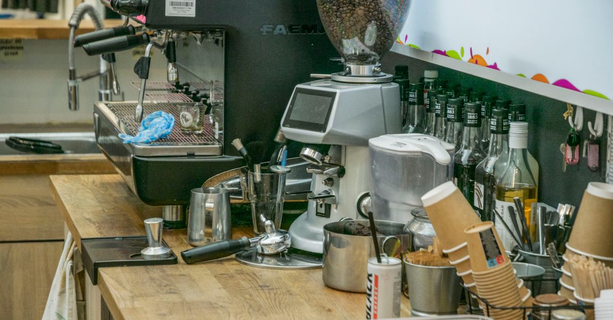 Coffee shop counter with espresso machine and ingredients, ready for brewing.